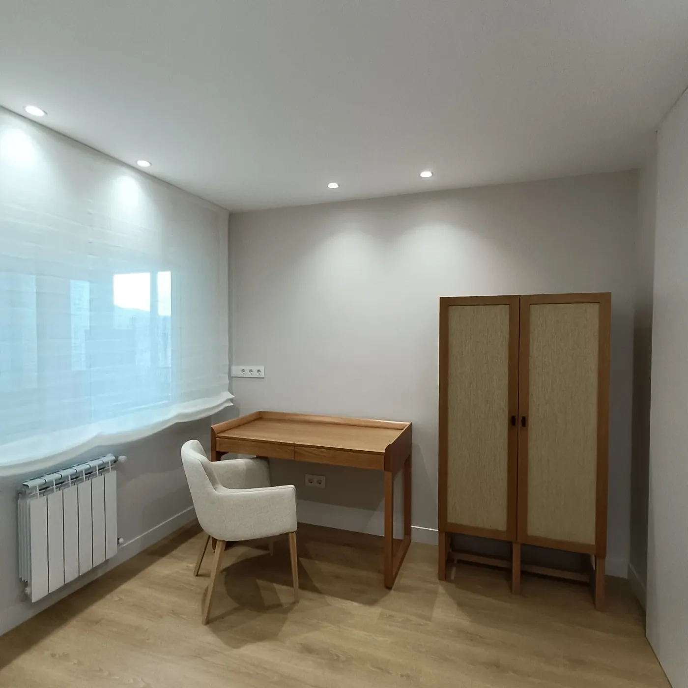 Estudio con escritorio de madera, silla tapizada y armario de rejilla