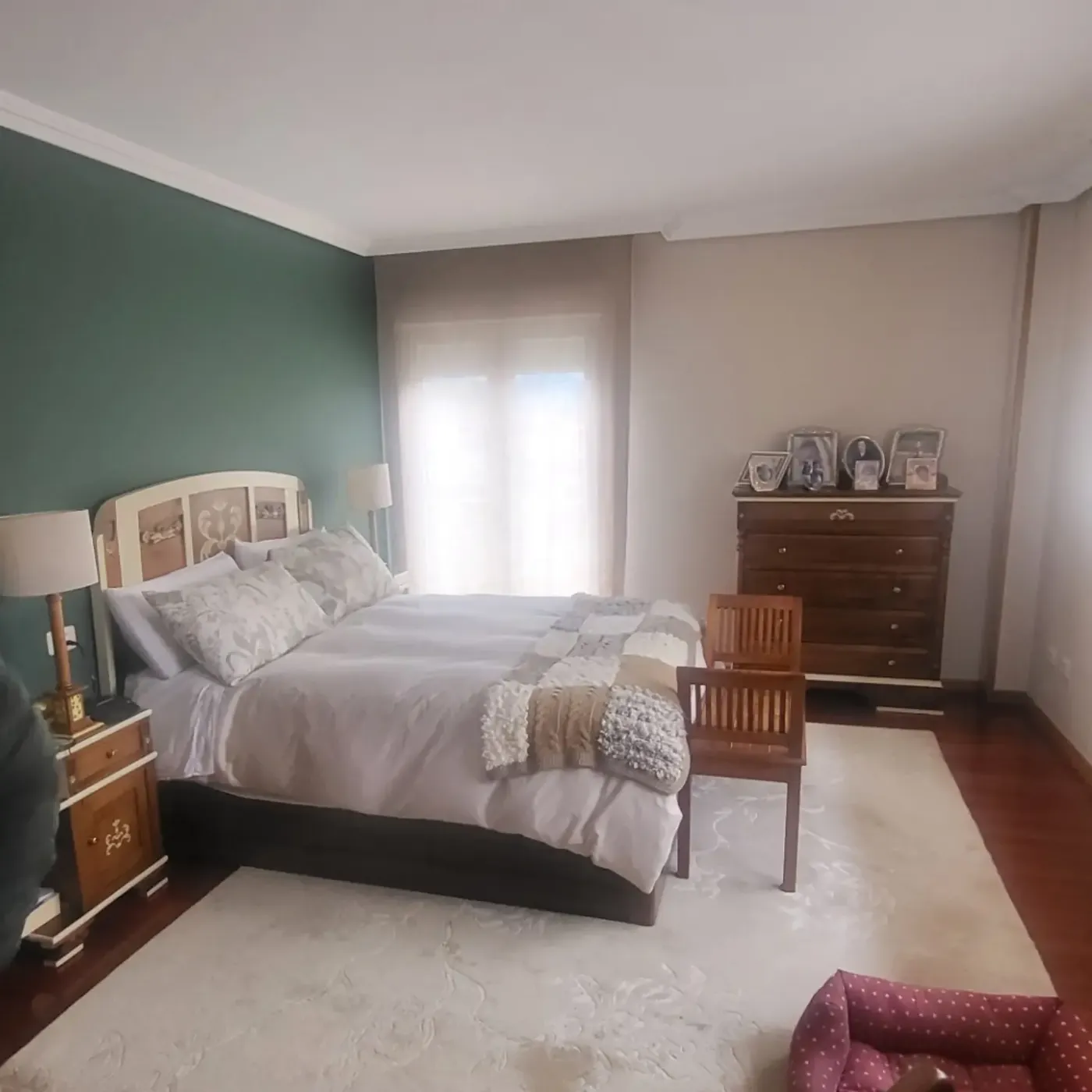 El dormitorio antes: pared verde, cabecero tallado y mobiliario oscuro