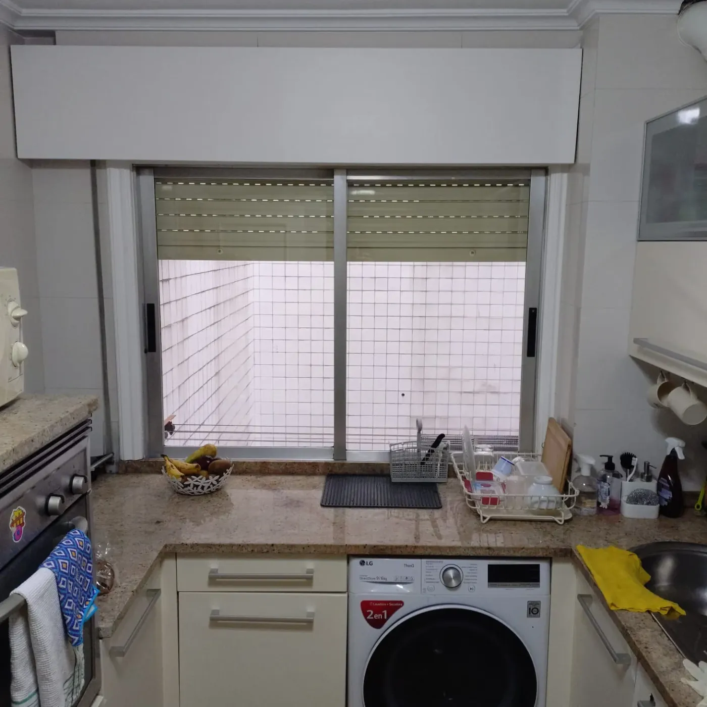 La cocina antes: encimera de granito y lavadora bajo la ventana