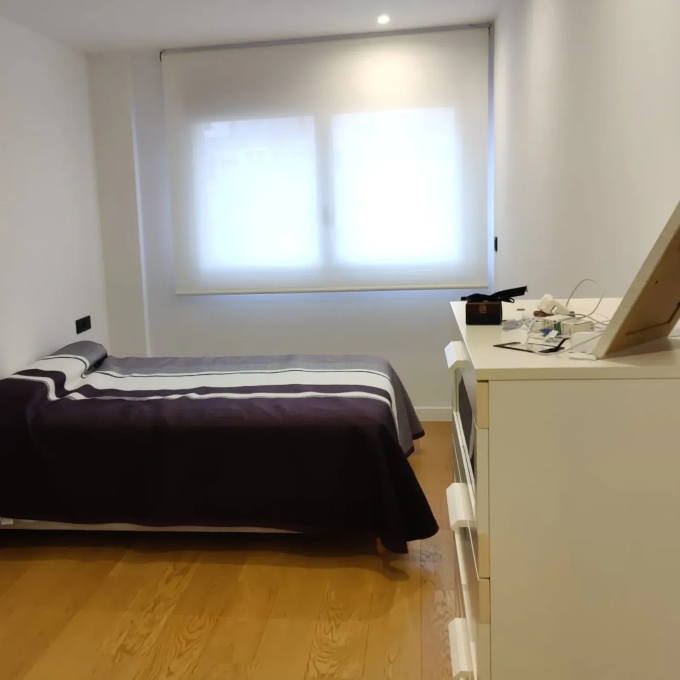 El dormitorio antes: colcha morada y mobiliario claro