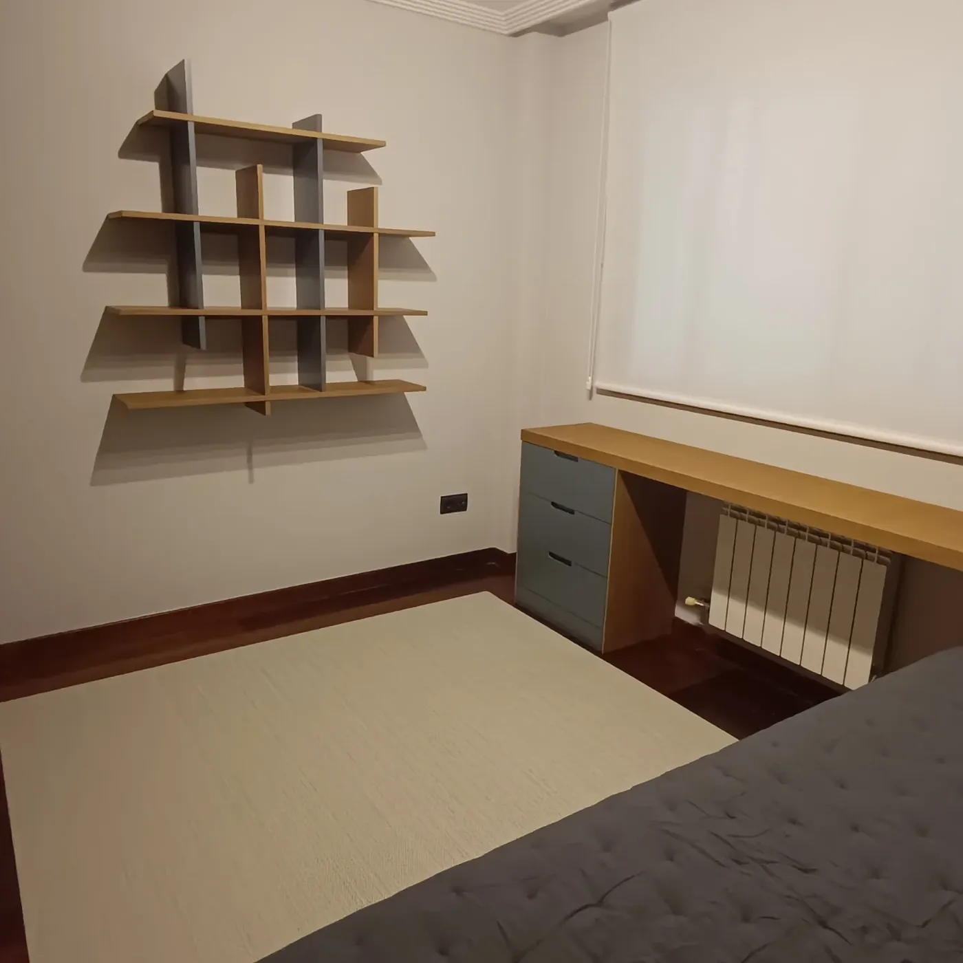 Estantería a medida sobre la cama y escritorio bajo la ventana