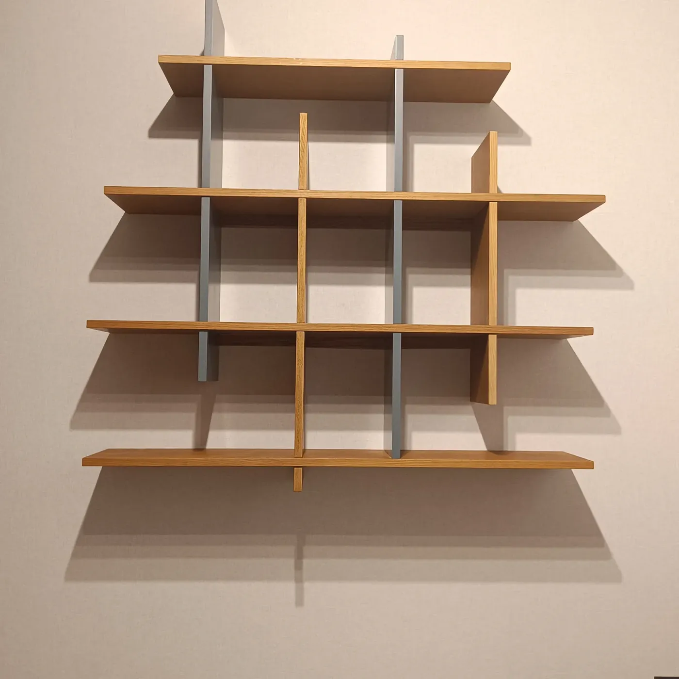 Detalle de la estantería a medida con baldas de madera y montantes grises
